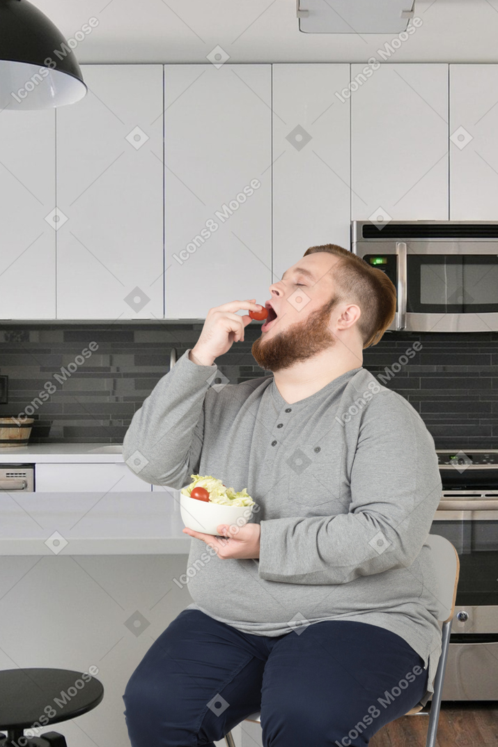 A man sitting in a chair eating a bowl of food