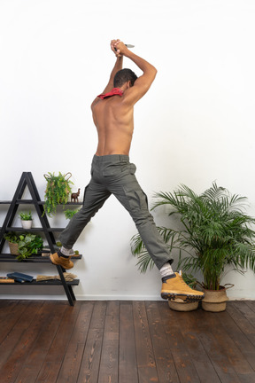 Strong man holding a knife with both hands jumping up