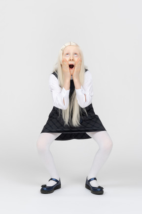 Schoolgirl holding her face and looking amazed