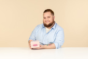 Grande homem sentado à mesa e segurando a lancheira