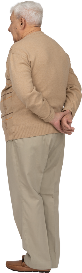 Rear view of an old man in casual clothes standing with hands behind back