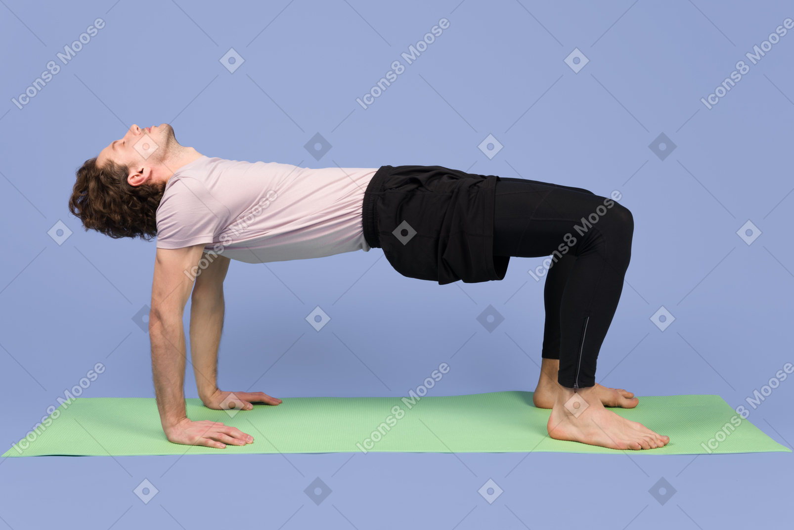 Apuesto joven de pie sobre sus piernas y manos en la estera de yoga