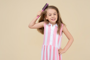 Cute little girl trying to brush her hair
