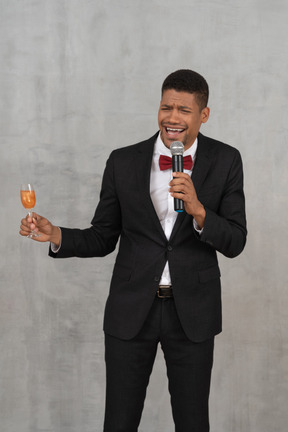 Confused-looking young man holding a microphone and champagne glass