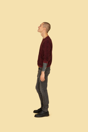 Side view of a funny grimacing young man in red sweater