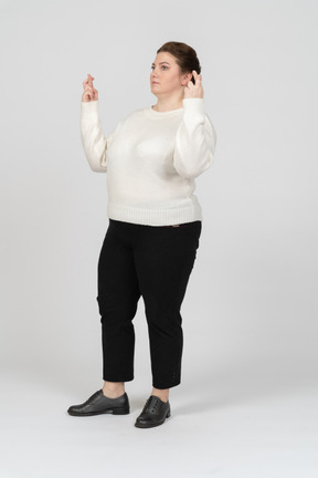 Vista lateral de uma mulher plus size com roupas casuais cruzando os dedos