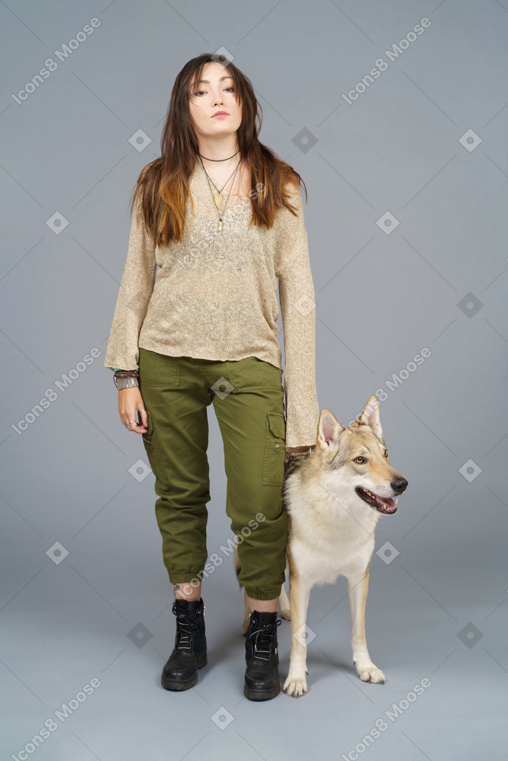 Full-length of a female master standing by her dog and looking at camera