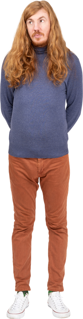 Vue de face d'un jeune homme en vêtements décontractés debout avec les mains derrière le dos