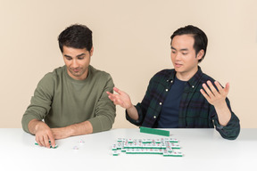 Interracial friends figuring out something while playing board game