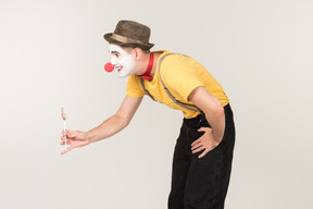 Smiling male clown passing lollipop he's holding