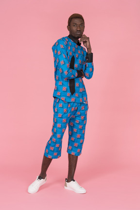 Black man in blue pajamas standing on pink background