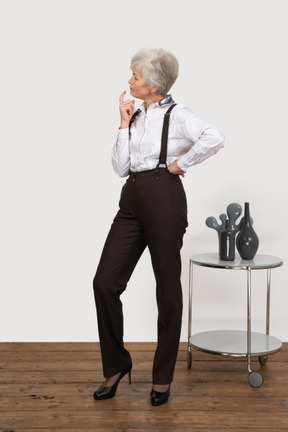 Vista lateral de uma senhora curiosa com roupas de escritório, inclinada para a frente