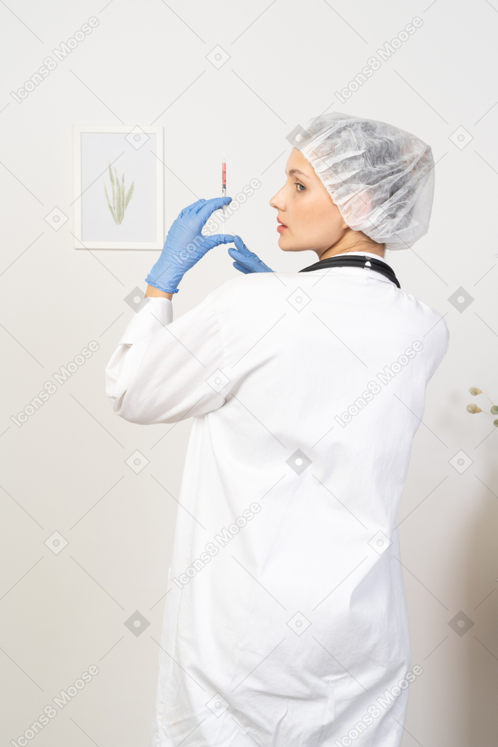 Back view of a young female doctor holding a syringe