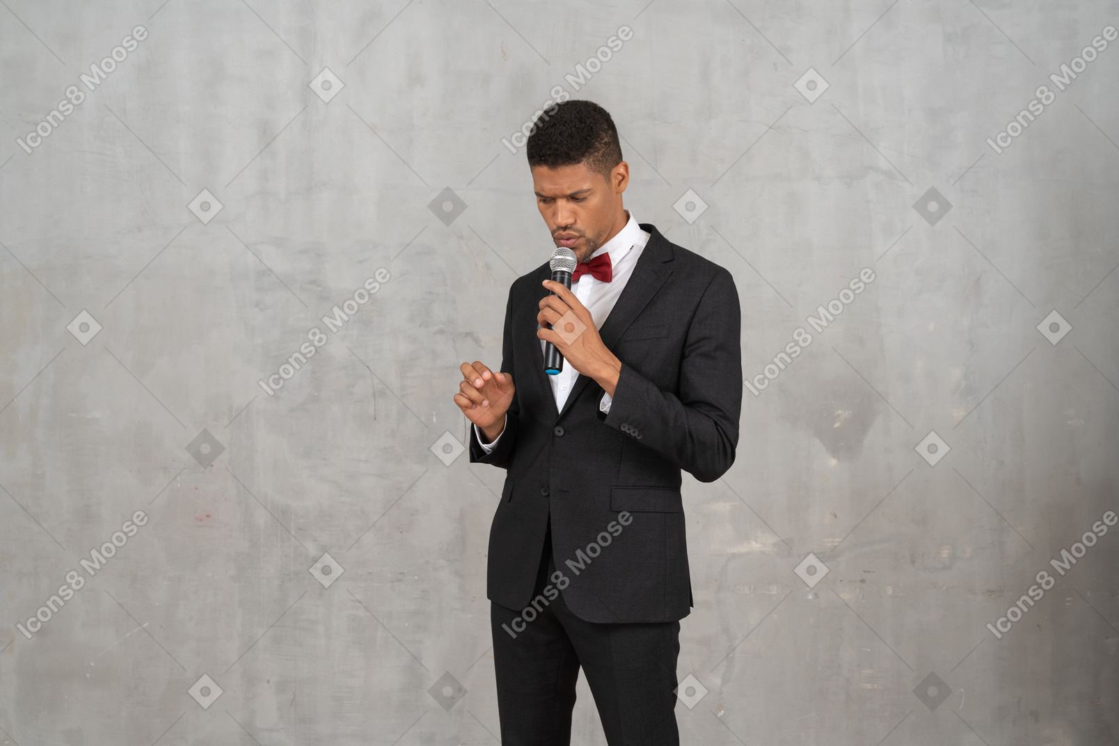 Hombre sombrío en traje negro sosteniendo un micrófono