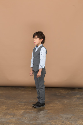 Vista lateral de un chico lindo en traje gris