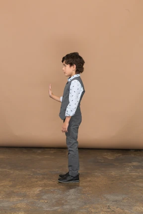 Side view of a boy in grey suit showing stop sign