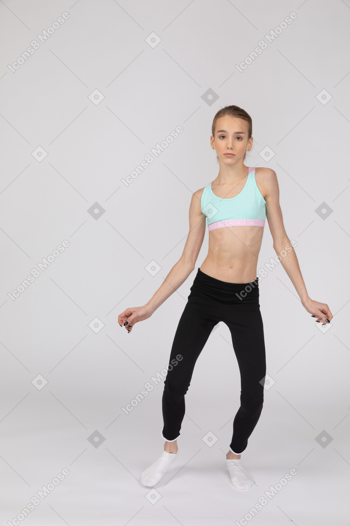 一个年轻的女孩，看着相机的运动服跳舞的前视图
