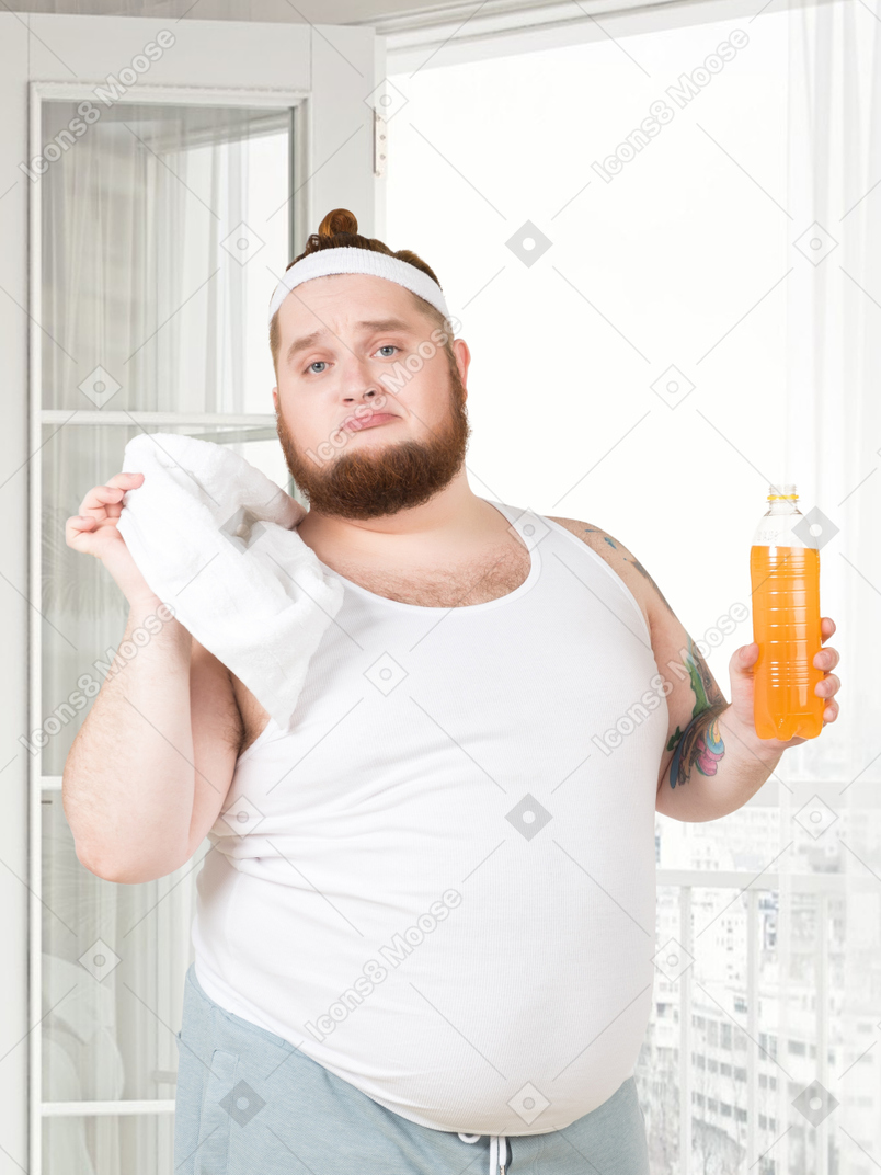 A fat man holding a bottle of orange juice