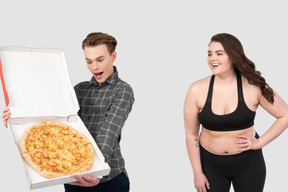 A man holding an open pizza box next to a woman
