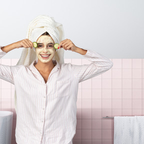 Woman with towel on her head applying face mask in the bathroom