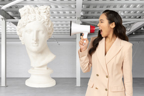 A woman holding a megaphone in front of a bust of a woman