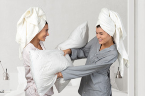 Two women fighting with pillows