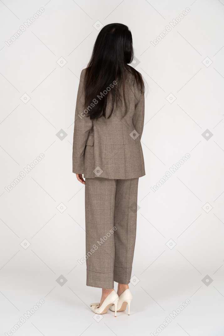 Three-quarter back view of a young lady in brown business suit looking aside