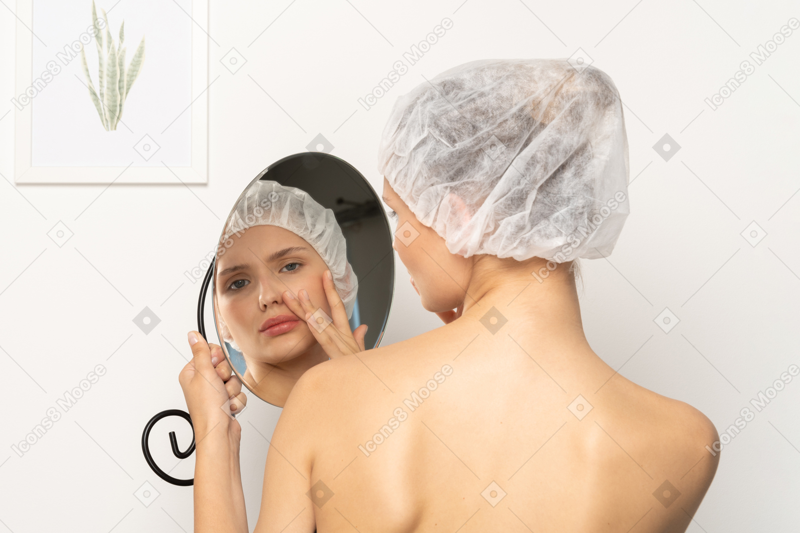 Young woman in surgical cap looking at herself in the mirror