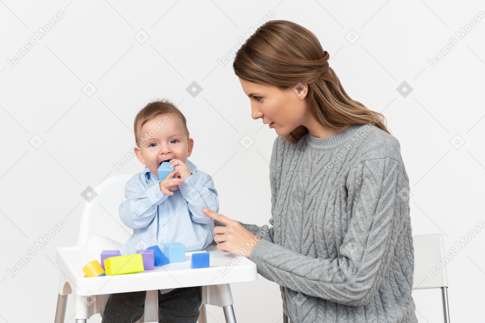 Young mother playing with his little son sitting in a highchair
