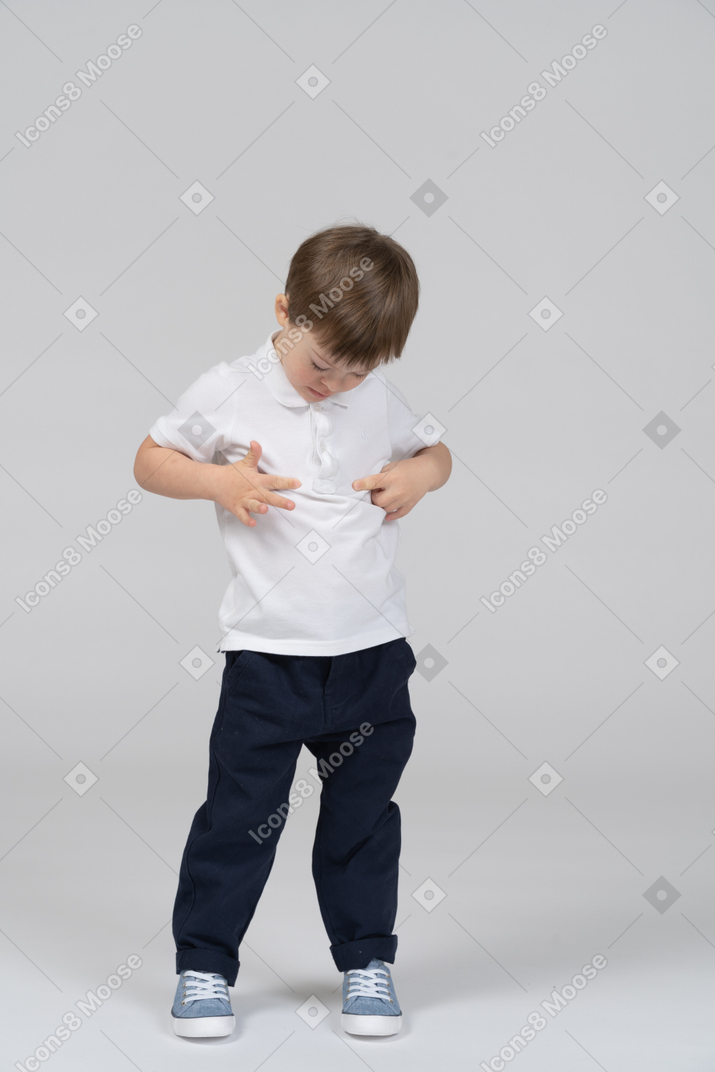 Niño pequeño tocando su estómago y mirando hacia abajo