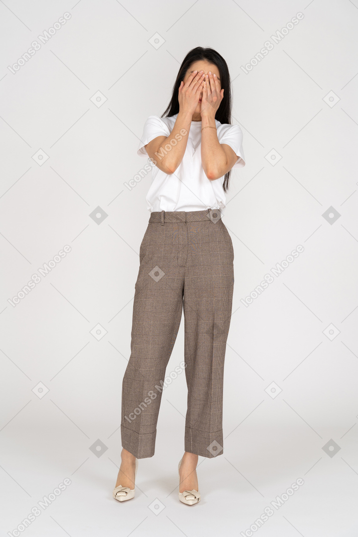 一位年轻的女士，穿着马裤和t恤，遮住她的脸的前视图
