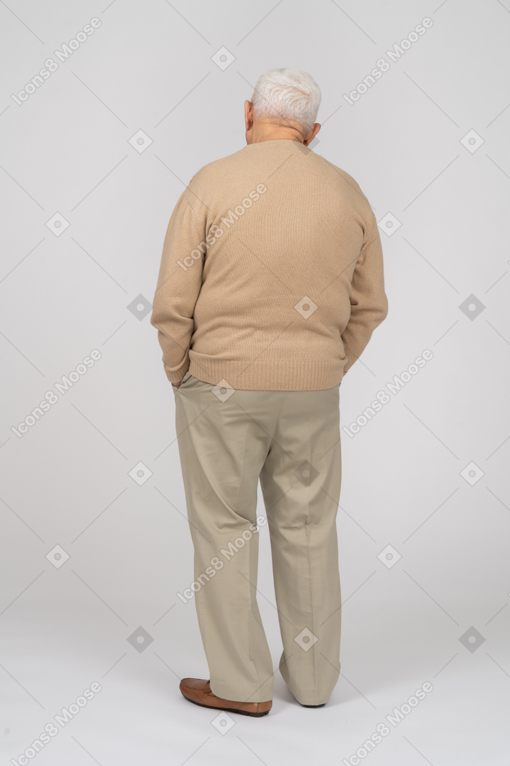 一位身穿休闲服、双手插在口袋里站着的老人的后视图