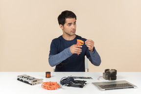 A young man in casual blue clothes working with computer details