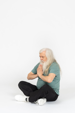 Three-quarter view of old man sitting and praying