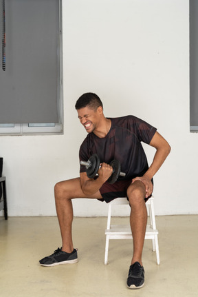 Young man in sports clothes lifting weigths