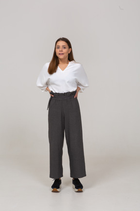 Front view of a young lady in office clothing pressing lips and putting hands on hips