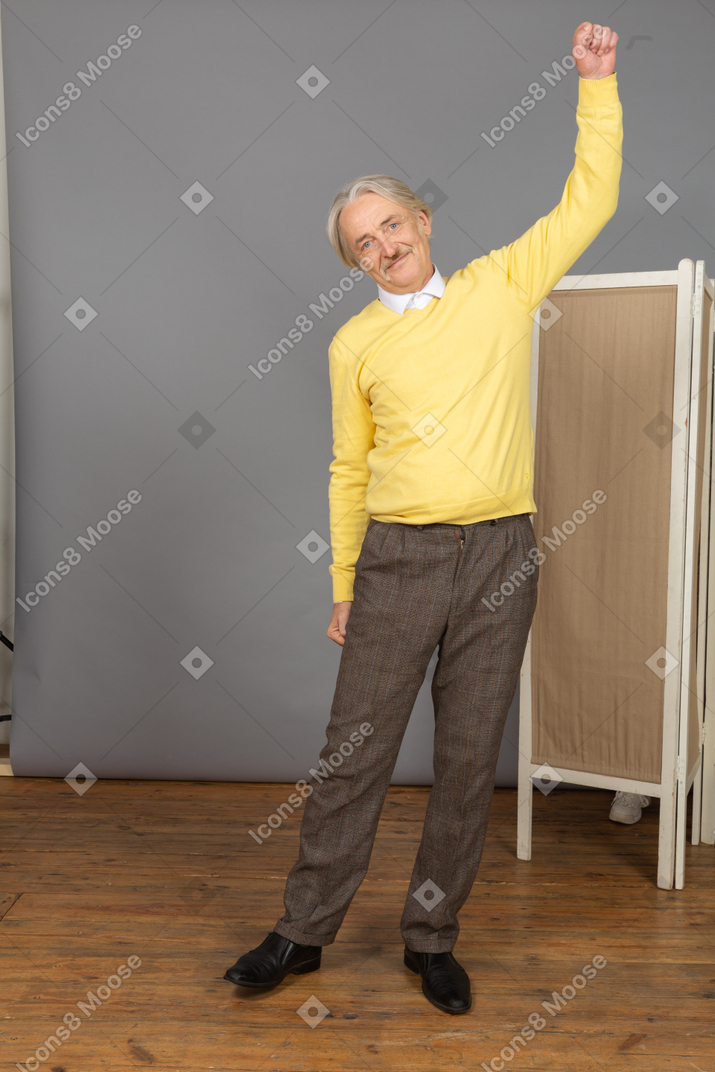 Front view of an old smiling man raising his hand