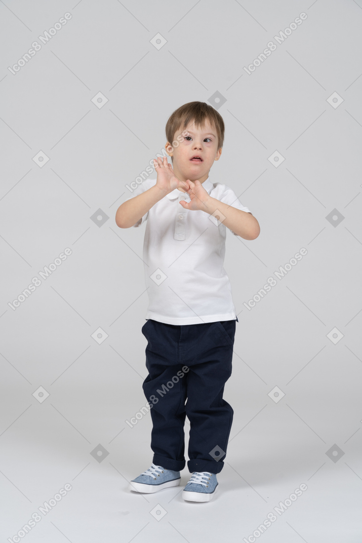 Surprised little boy standing with his hands up