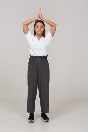 Front view of a young lady in office clothing holding hands together over her head