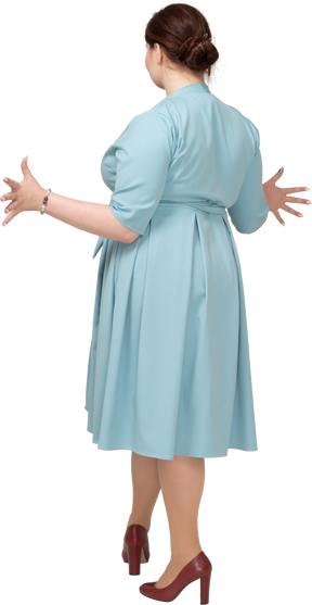 Женщина в синем платье жестикулирует, вид сзади