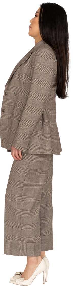 Side view of a confused young lady in brown business suit leaning back