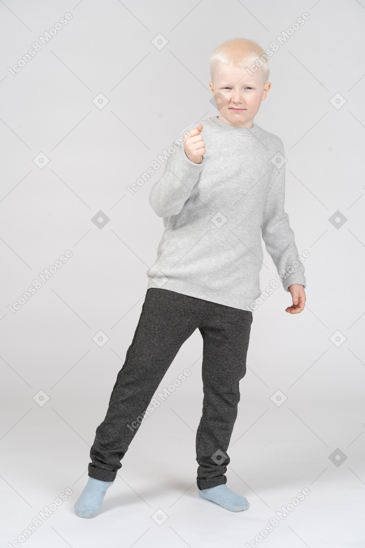 Little boy looking at camera with his fist raised