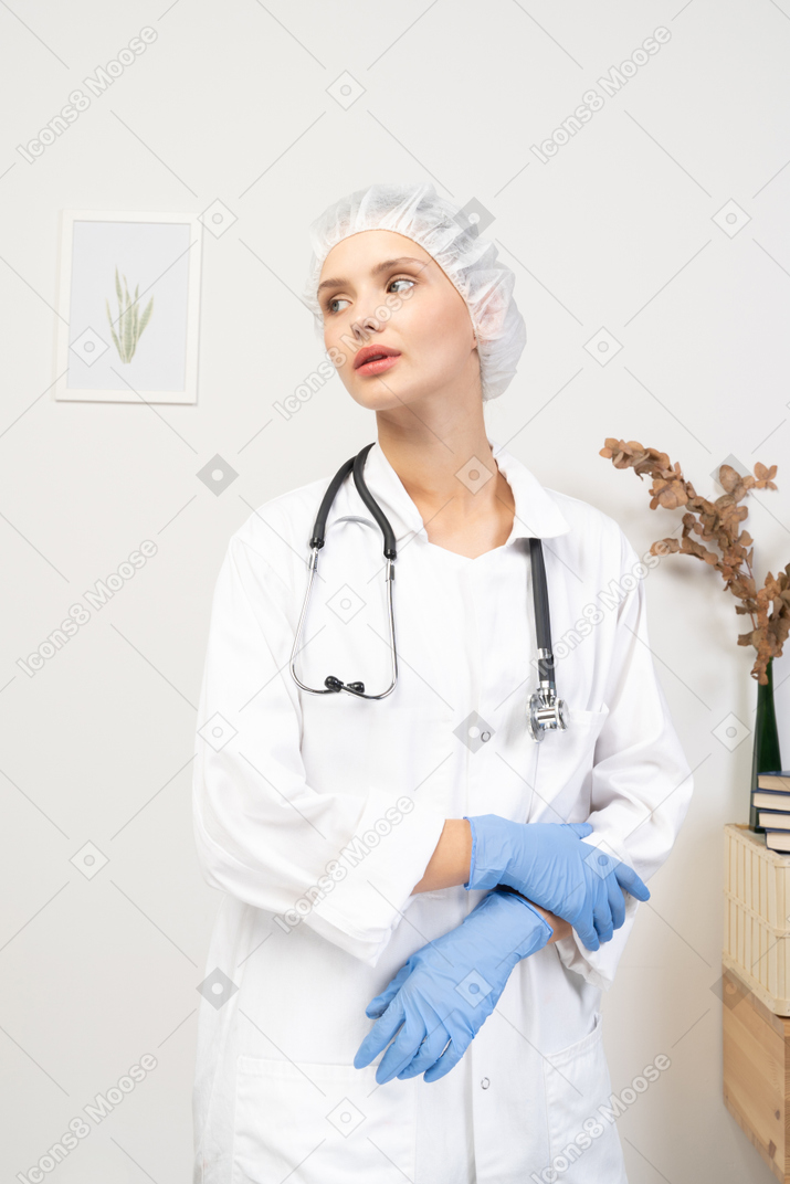 Front view of a tired young female doctor with stethoscope holding hands together