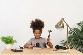 Jolie fille essayant de réparer un vieil appareil photo à la table