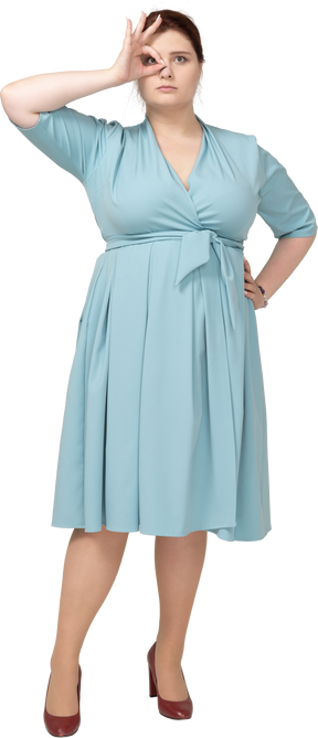 Vista frontal de uma mulher de vestido azul olhando por entre os dedos