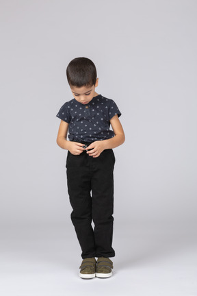 Вид спереди симпатичного мальчика в повседневной одежде, смотрящего на руки