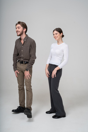 Vue de trois quarts d'un jeune couple en riant dans des vêtements de bureau