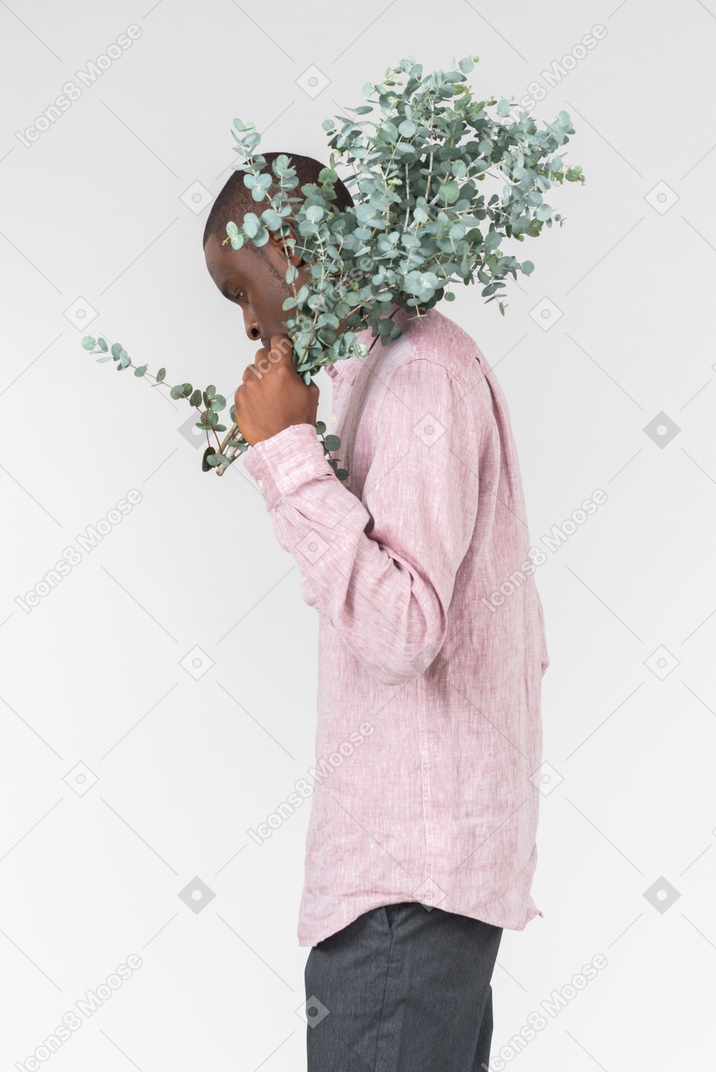 Good looking young man holding green branches