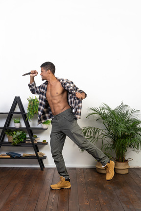 Side view of a tourist in an unbuttoned shirt threatening with a knife