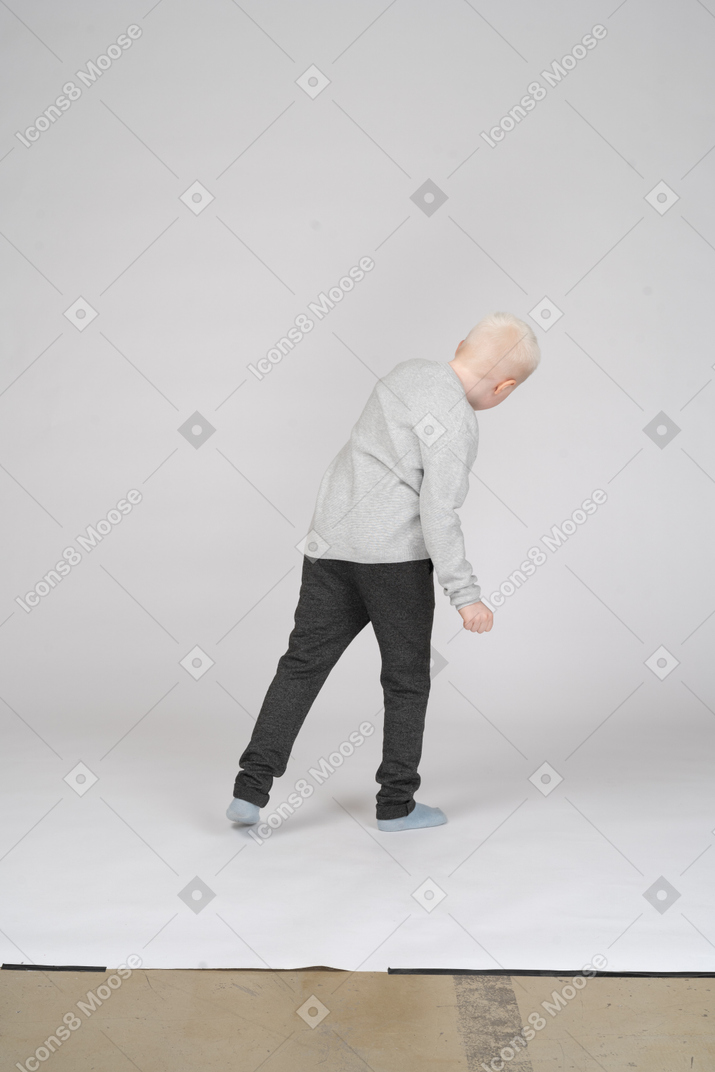 Вид сзади на мальчика в повседневной одежде, наклонившегося вниз